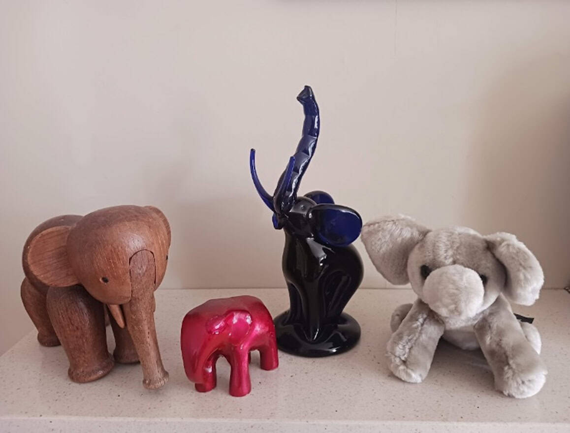 Four different kinds of toy elephants, ceramic, stuffed, plastic and wood